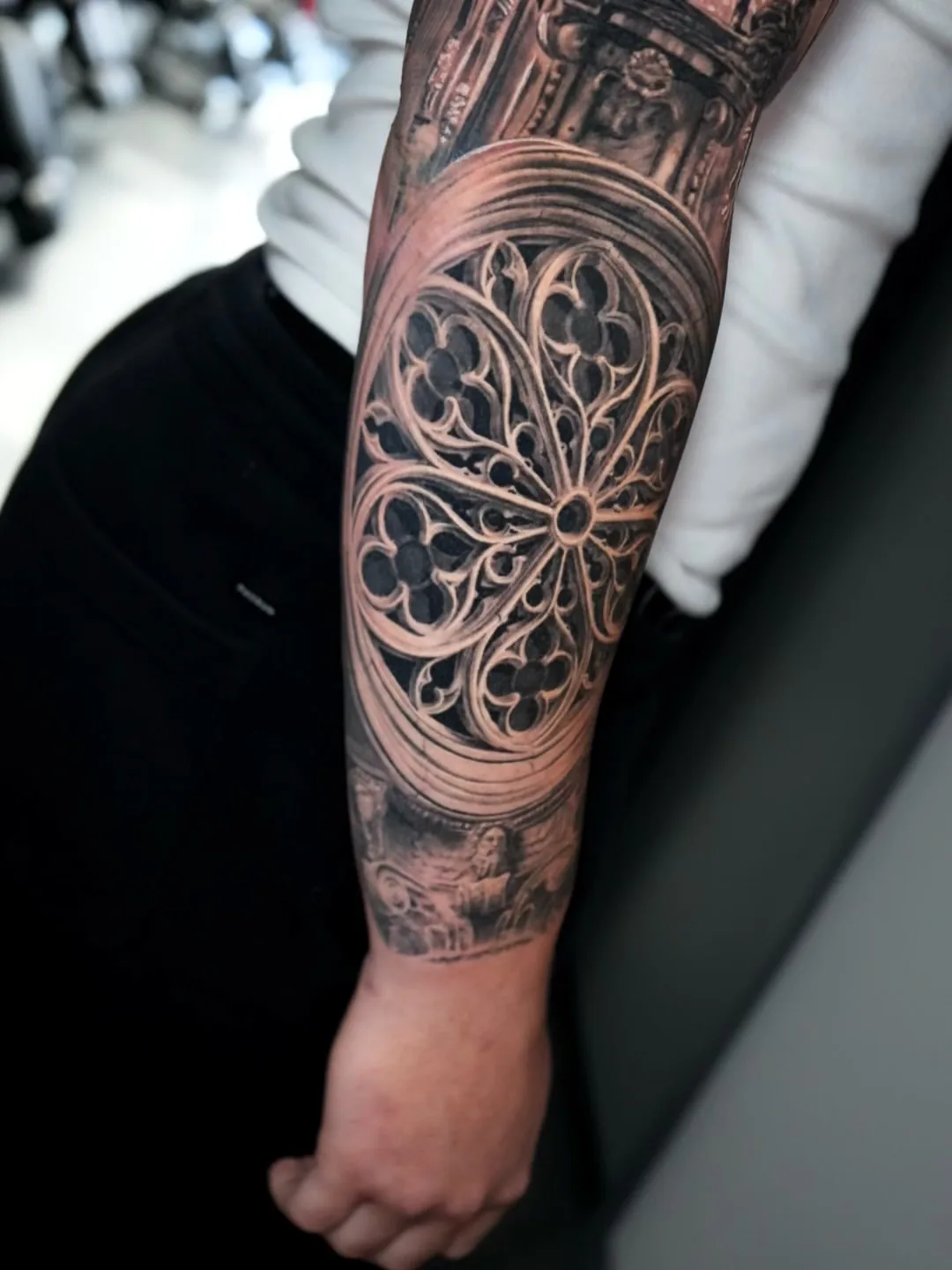 Gothic rose window forearm tattoo in black and grey