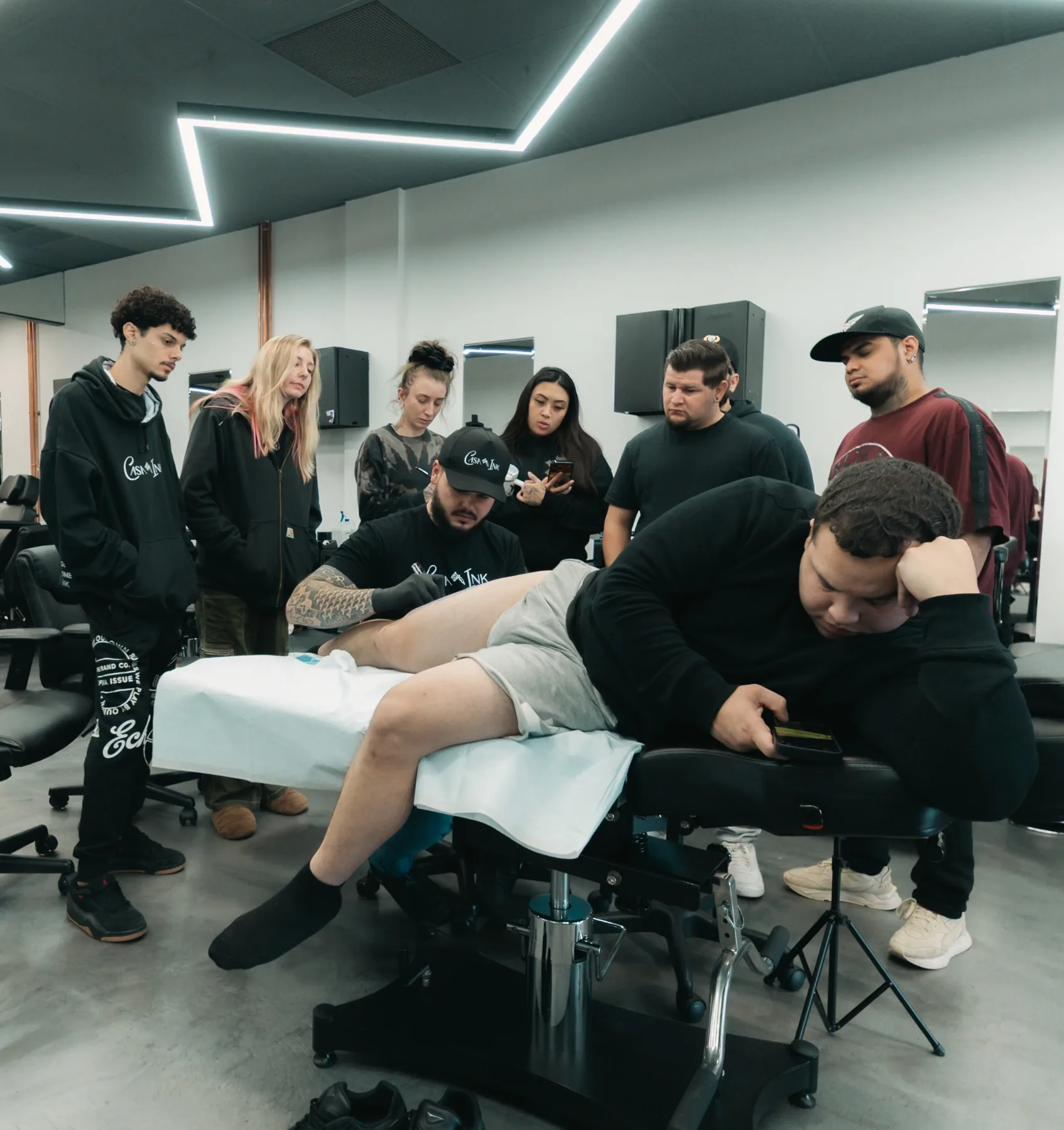 Vinny Garcia tattooing a client while workshop attendees watch